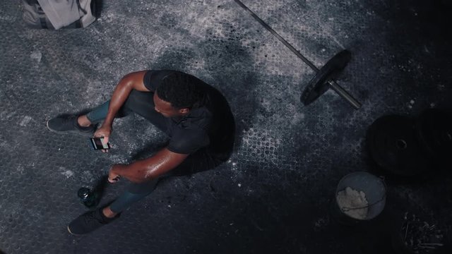 fitness man athlete using smartphone browsing online sharing fitness lifestyle on social media checking messages resting after workout exercise in gym top view