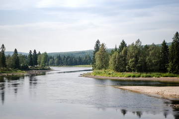 aerial view of river and evergreen trees on shores in sunlight, Trysil, Norway's largest ski resort