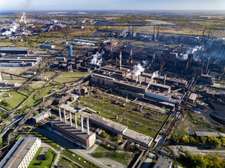 Fototapeta premium Concept of environmental pollution, drone view of smokestack pipe steel plant, aerial industrial panoramic landscape with blue sky and autumn vegetation, air emissions from manufacturing sector,Russia