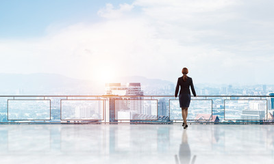 Sunrise above skyscrapers and businesswoman facing new day