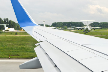 View from a window on a wing during typesetting of speed and coming off the earth on the runway. There are three planes on a background.