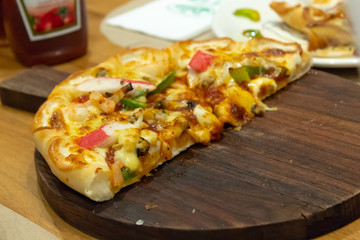 Pizza on a wood tray on table.