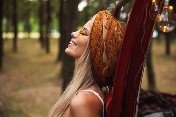 Photo of european hippie woman, wearing stylish accessories looking aside while resting in forest...