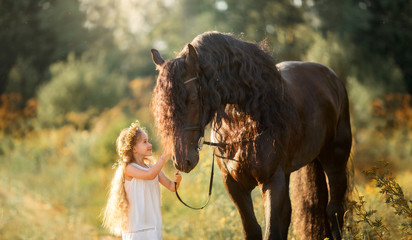 Little  girl with black friesian stallion 