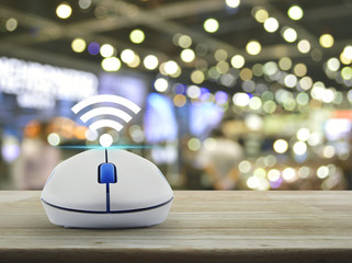 Wi-fi button with wireless computer mouse on wooden table over blur light and shadow of shopping...