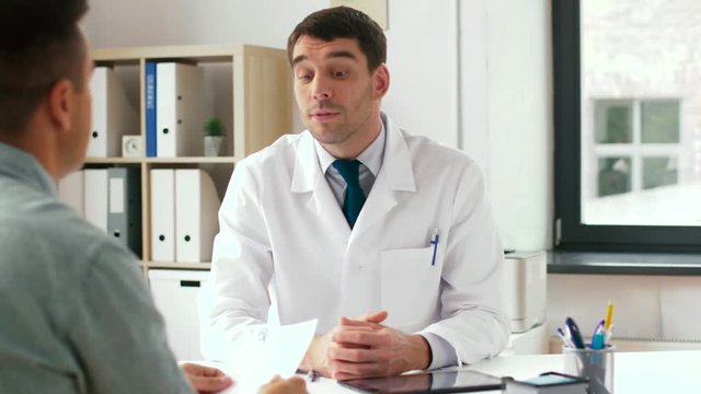 medicine, healthcare and people concept - doctor and male patient with prescription at clinic