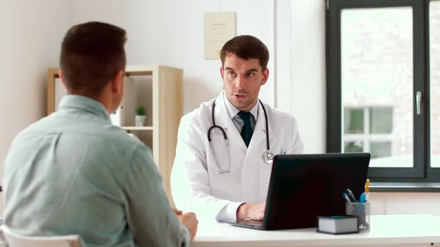 medicine, healthcare and technology concept - doctor with laptop computer and male patient talking at hospital