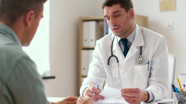 medicine, healthcare and people concept - doctor giving prescription for male patient at clinic