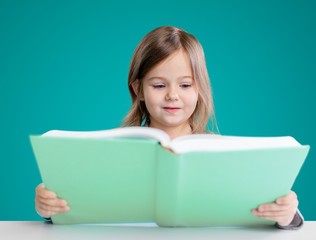 Adorable young girl reading a book