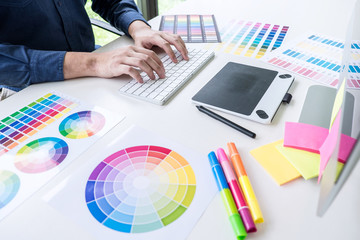 Male creative graphic designer working on color selection and color swatches, drawing on graphics...