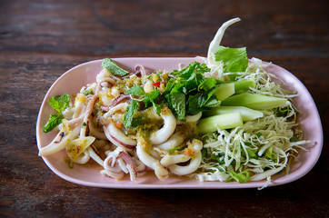 Squid spicy and sour salad wood table background, thai traditional food , thai seafood cuisine, image for menu list,background,wallpaper and copy space