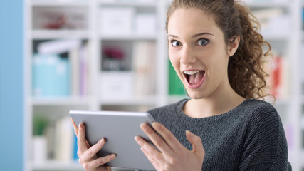 Surprised cheerful girl connecting with her tablet