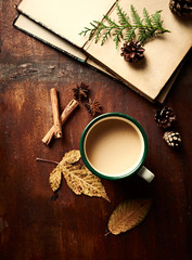 Mug of hot coffee with milk and spices and autumn leaves on wooden table. Flat lay. Copy space