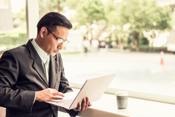 Asia business man working with laptop while sitting coffee shop .Concept of young  business people