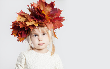 Cute little girl with autumn leaves on background with copy space