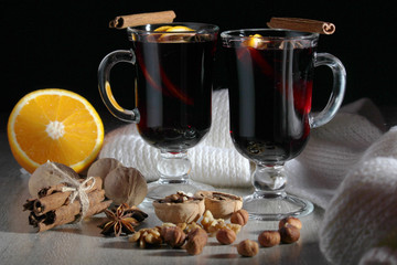 Two cups with ready mulled wine with anise, cinnamon and nuts around