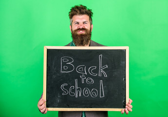 School and studying concept. Teaching occupation demands talent and experience. Teacher welcomes students while holds chalkboard inscription back to school. Positive moments and issues teaching work