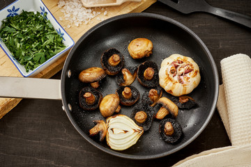 delicious fried mushrooms on a hot pan on an old wooden black table