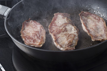 Filetes de cerdo ibérico friéndose en la sartén.