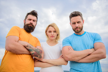 Strength in unity. Threesome stand confidently with folded arms. Threesome look down at you. Behaviors of cohesive team. Ways to build сohesive team. Woman and men look confident sky background