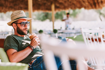 Young man drinking ice coffee in a beach bar