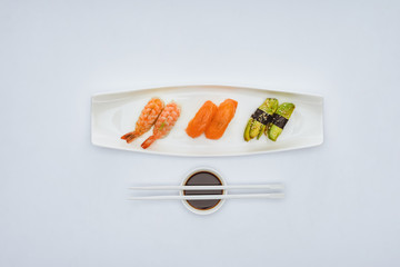 top view of gourmet sushi, soy sauce and chopsticks isolated on white