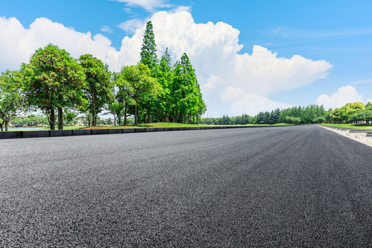 Empty asphalt road and green woods under blue sky