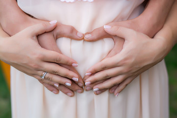 Pregnant belly. Hands on the pregnant. Heart from hands on stomach. Waiting for the baby