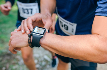 Unrecognizable sportsman looking at a smartwatch during a race