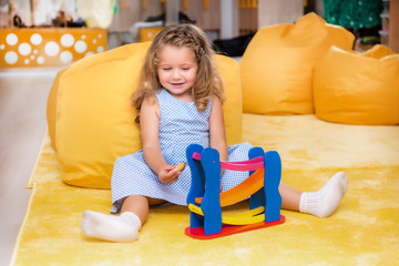 happy adorable child sitting on carpet and playing with toy in kindergarten