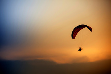 Skydiving sunset landscape of parachutist flying in soft focus. Para-motor flying silhouette with sun set. Silhouette of paraglider flying in the evening sky with sunset.