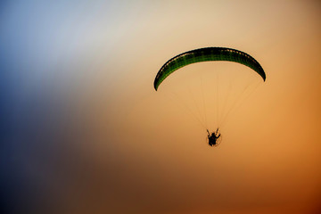 Skydiving sunset landscape of parachutist flying in soft focus. Para-motor flying silhouette with sun set. Silhouette of paraglider flying in the evening sky with sunset.