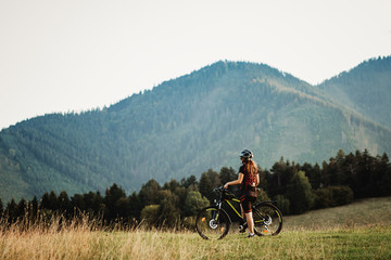 Fototapeta premium cyclist amiring mountain view facing away from the camera 