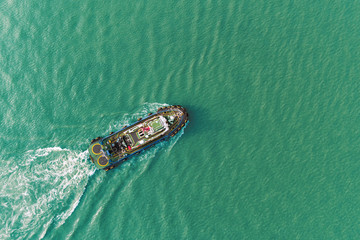 Tug boat on the sea driving for push ship container for transportation background.