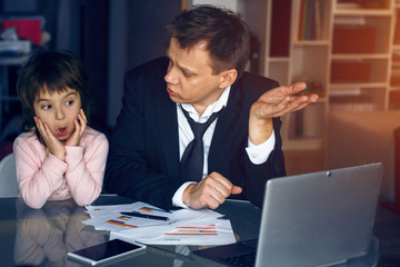 Little girl looking at laptop with surprise while her father asking her questions. Business at home concept.