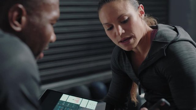 healthy woman trainer using tablet computer sharing performance results to athletes enjoying workout motivation in gym meeting fitness bodybuilding lifestyle