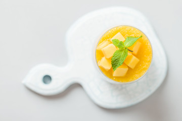 Chia seeds pudding with mango puree in beautiful glasses with green mint leaves and cut fresh ripe...