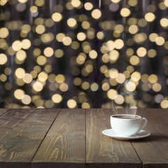 Warming cup of hot black coffee on wooden table in cafe. Blurred gold garland as background. Christmas Time. Image for display or montage your products.