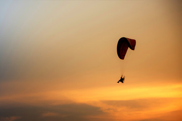 Skydiving sunset landscape of parachutist flying in soft focus. Para-motor flying silhouette with sun set. Silhouette of paraglider flying in the evening sky with sunset.