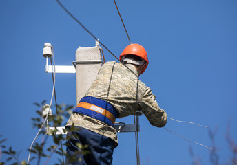 electrician worker on a pole with wires, electricity repair works