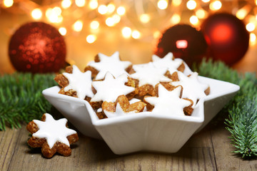 Cinnamon stars in star-shaped bowl as a spice for Christmas with fairy lights as decoration and lighting