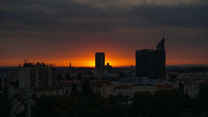 Fototapeta na wymiar View of city buildings against cloudy sky during sunrise in Vienna / Spittelau on a summer morning