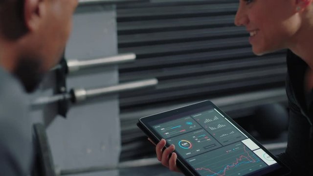 fitness woman trainer using tablet computer sharing performance results to athletes enjoying workout motivation in gym meeting healthy bodybuilding lifestyle