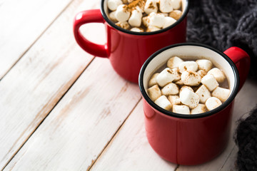 Christmas cocoa with marshmallow in mug on white wooden table. Copyspace