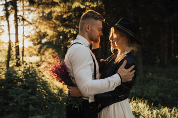 Fototapeta premium Hipster wedding couple kissing in forest in sunset light in fog