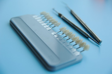 Dental equipment for the selection of a shade and color of teeth closeup on a blue background