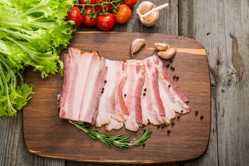 Slices of bacon on the wooden background