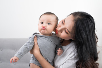 Young mother with her one years old little son dressed in pajamas are relaxing and playing in the living room at the weekend together, lazy morning, warm and cozy scene. Selective focus.