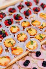 Delicious raspberry, peaches mini tarts (tartlets) with whipped cream on dark background