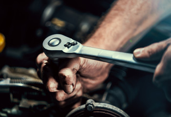 Auto mechanic working on car engine in mechanics garage. Repair service. authentic close-up shot